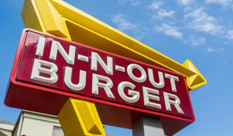In-N-Out Burger restaurant sign with yellow arrow against blue sky background