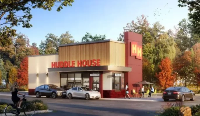 Rendering of a modern Huddle House drive-thru restaurant with autumn foliage, parked cars, and outdoor seating.