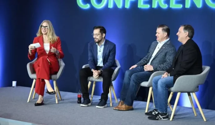 Four restaurant industry executives and a moderator sit on stage during a panel discussion at the Global Restaurant Leadership Conference 2025, discussing international expansion challenges and strategies. A large backlit “CONFERENCE” sign glows behind them.