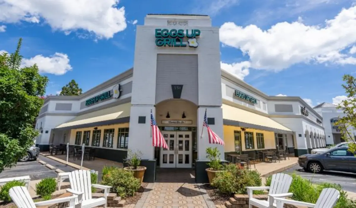 Exterior of an Eggs Up Grill restaurant with outdoor seating under a bright blue sky.